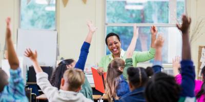 Children with hands up in class