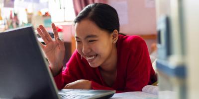 Student waving on laptop