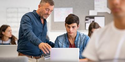 Student and teacher looking at laptop