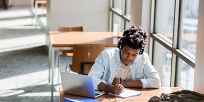 Student working with technology and writing