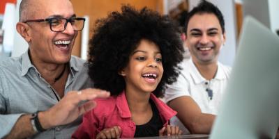 Family of three looking at a laptop and smiling.