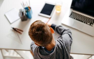 Student sitting at desk at home with technology