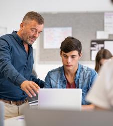 Student and teacher looking at laptop